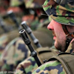 Ist die Wehrpflicht eine zeitgemäße Lösung? (Foto „Mann in Tarnuniform“ von Simon Infanger @ Unsplash)